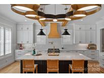A gourmet kitchen featuring a large island, custom cabinets, and designer lighting, offering modern amenities at 3228 E Ford Rd, Charlotte, NC 28205