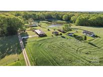 Expansive estate with multiple buildings, pond, and surrounding green fields and forests at 36984 B&C Carter Rd, New London, NC 28127