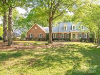 Charming brick home featuring dormer windows, mature trees, and a beautifully landscaped front yard at 3815 Glen Haven Sw Dr, Concord, NC 28027