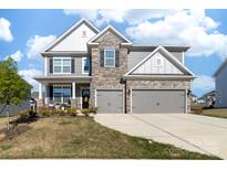 Charming two-story home featuring a stone facade, gray siding, covered porch, and a two-car garage at 8143 Warford Little Rd, Denver, NC 28037