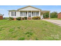 Charming one-story home featuring a covered porch, attached carport, and a well-maintained front lawn at 1504 Andicot Ln, Shelby, NC 28152