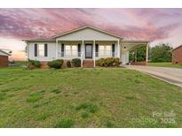 Charming one-story home with a covered porch and carport set on a well-manicured lawn under a dramatic sky at 1504 Andicot Ln, Shelby, NC 28152