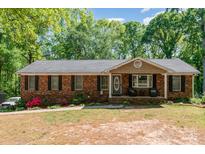 Charming brick home featuring a well-manicured lawn and an inviting front porch, perfect for relaxing at 1565 Oakridge Dr, Salisbury, NC 28146