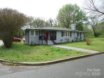 Charming single-story home featuring a red front door, gray brick, and landscaped yard with mature trees at 412 E Broad St, Salisbury, NC 28144
