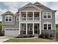 Charming two-story home with an inviting front porch, stone accents, and a well-manicured lawn at 10035 Mast Cove Ln, Charlotte, NC 28278