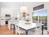 Eat-in kitchen featuring a breakfast bar, white cabinets, and stainless steel appliances, plus sliding glass doors and view at 220 Chandeleur Dr, Mooresville, NC 28117