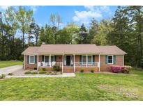 Charming brick ranch with inviting front porch and beautifully landscaped yard in a serene, wooded setting at 504 Ogden Dr, Gastonia, NC 28056