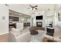 A staged living room featuring a fireplace, ceiling fan and hardwood floors at 740 Rosegate Dr, Gastonia, NC 28056