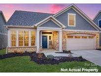 Charming home with stone accents, a two-car garage and well-manicured lawn at 7549 Baybrooke Ln # 32, Harrisburg, NC 28075