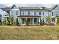 Charming townhome featuring a covered porch, gray siding, and manicured landscaping at 10209 Meeting House Nw Dr, Huntersville, NC 28078