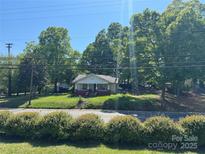 Charming one-story home set amongst mature trees, featuring a classic front porch design and welcoming curb appeal at 1203 N Charlotte Ave, Monroe, NC 28110
