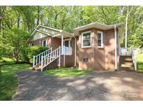 Charming brick home featuring a well-manicured lawn, complemented by lush trees and a welcoming entryway at 1730 Deer St, Charlotte, NC 28214