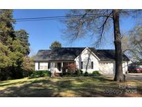 Charming home featuring a well-manicured lawn, covered porch, and attached two-car garage at 215 Raleigh Nw St, Concord, NC 28027