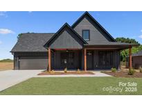 Stylish home with vertical siding, covered porch, green lawn, and attached two-car garage at 32531 Buchanan Ln, Albemarle, NC 28001