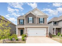 Charming two-story home features a two-car garage and professionally landscaped front yard with green shutters at 352 Runner Stone Ln, Fort Mill, SC 29715