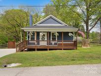 Charming blue home featuring a cozy front porch and beautifully landscaped front yard at 402 Sidney Johnson St, Fort Mill, SC 29715
