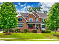 Traditional two-story brick home featuring a landscaped lawn, covered front porch, and mature trees at 4711 Pearmain Dr, Waxhaw, NC 28173