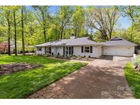 Charming exterior of a white brick home with a well-manicured lawn and attached two-car garage at 641 Charter Pl, Charlotte, NC 28211