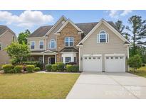 Charming home with a two-car garage, well-manicured lawn, and lush landscaping at 8923 Happiness Rd, Harrisburg, NC 28075
