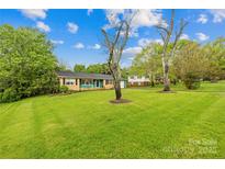 Landscaped front yard featuring a charming single-story home with blue and brick accents at 1204 Meadowood Dr, Shelby, NC 28150
