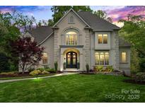 Stunning two-story home featuring manicured lawn and stone facade, complemented by lush landscaping at 2500 Giverny Dr, Charlotte, NC 28226