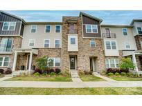 Beautiful three-story townhome featuring stone accents and manicured landscaping at 2533 Ensemble Ct, Charlotte, NC 28262