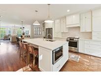 Bright white kitchen featuring a large center island with barstool seating, stainless appliances, and open to the living spaces at 2621 Huntman Way, Charlotte, NC 28226
