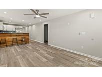 Spacious living room with wood-look flooring, ceiling fan, and bar area open to the modern kitchen at 109 W Poplar St, Stanley, NC 28164