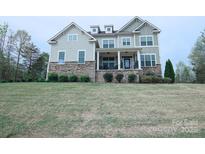 Charming two-story home featuring stone accents, a welcoming front porch, and a lush green lawn at 126 Rain Shadow Dr, Mooresville, NC 28115