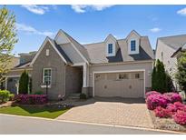 Charming home boasts stone accents, dormer windows, and a well-manicured front yard with colorful flowers at 17728 Jetton Green Loop, Cornelius, NC 28031