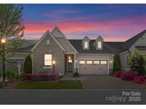 Charming home boasts stone accents, dormer windows, and a well-manicured front yard with colorful flowers at 17728 Jetton Green Loop, Cornelius, NC 28031