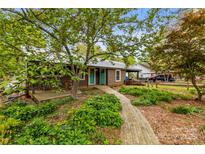 Charming cottage with a wooden walkway and a front porch with a wooded landscaped yard and teal front doors at 2106 4Th Ne St, Hickory, NC 28601