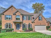 Traditional two-story brick home featuring a manicured lawn, attached garage, and charming front entryway at 213 Walnut Point Dr, Matthews, NC 28105