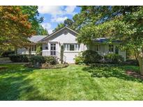 Charming brick home with a beautifully landscaped front yard and mature trees under a blue sky at 311 Mcalway Rd, Charlotte, NC 28211