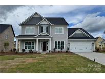 Charming two-story home with a gray exterior, a well-manicured lawn and an attached two car garage at 4038 Gardenia Dr # 0114, Harrisburg, NC 28075