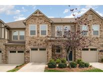 Charming townhome featuring stone accents, a tan garage door, and a well-maintained yard at 5684 Garrow Glen Rd # 96, Charlotte, NC 28278