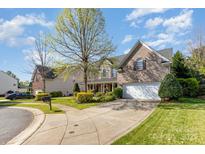 Charming brick home featuring a manicured lawn, inviting driveway, and attached two car garage at 6941 Augustine Way, Charlotte, NC 28270