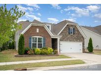 Charming brick and stone home with a manicured lawn and a two-car garage, situated beneath a partly cloudy sky at 3028 Quinebaug Rd, Fort Mill, SC 29715
