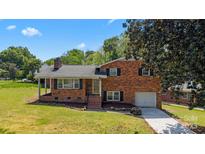 Charming brick home with a well-manicured lawn, attached garage, and inviting front porch under a sunny, blue sky at 5301 Baker Dr, Charlotte, NC 28210