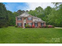 Charming two-story brick home featuring a well-manicured lawn and mature landscaping with blooming azaleas at 7206 Forrest Rader Dr, Mint Hill, NC 28227