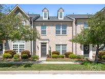 Charming townhome boasts beautiful brick facade, manicured landscaping, and inviting entrance at 11447 Potters Row, Cornelius, NC 28031
