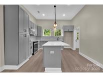 A spacious kitchen featuring gray cabinets, a central island, modern countertops, and stainless steel appliances at 126 Hemphill Ave, Chester, SC 29706