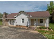 Charming single-Gathering home featuring a stone chimney, covered porch, and white vinyl siding at 1501 Nc Hwy 73 Hwy, Iron Station, NC 28080