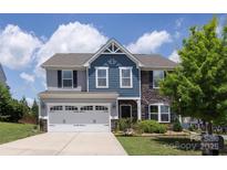 Charming two-story home with a manicured lawn, two car garage, and a mix of stone and blue toned siding at 7397 Mill Ruins Sw Ave, Concord, NC 28025