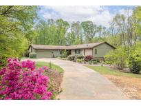 Charming single-story home featuring a long driveway and lush landscaping at 78 N Scalybark Trl, Concord, NC 28027