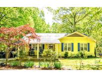 Charming yellow home featuring a covered porch with rocking chairs and beautifully landscaped front yard at 2929 Matoka Trl, Matthews, NC 28104