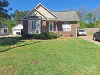 Charming single-story brick home with a well-maintained front yard and a detached garage in the background at 400 N Main Gq St, Granite Quarry, NC 28146