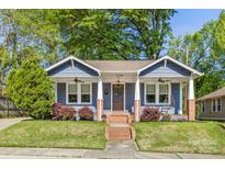 Charming blue home with a quaint front porch, swing, brick accents, and beautiful landscaping at 1716 Wickford Pl, Charlotte, NC 28203