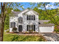 Charming two-story home boasts a manicured lawn, black shutters, and attached two car garage at 1807 Sugar Hollow Dr, Charlotte, NC 28214