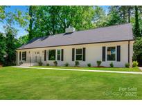 Charming home featuring a classic white brick exterior, black shutters, and a lush green lawn at 2601 Pinewood Rd, Gastonia, NC 28054